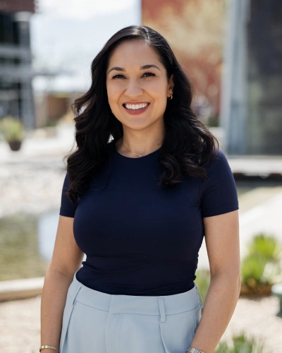 Woman in navy shirt smiling outdoors with urban backdrop for Adventure Smiles.