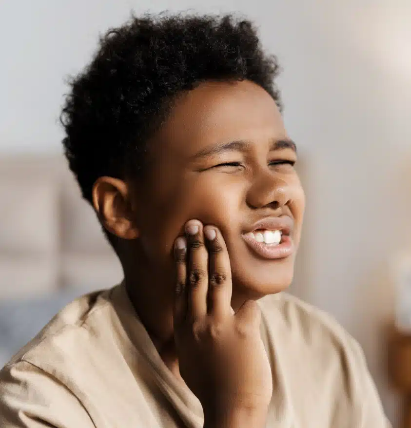 Child holding cheek with tooth pain